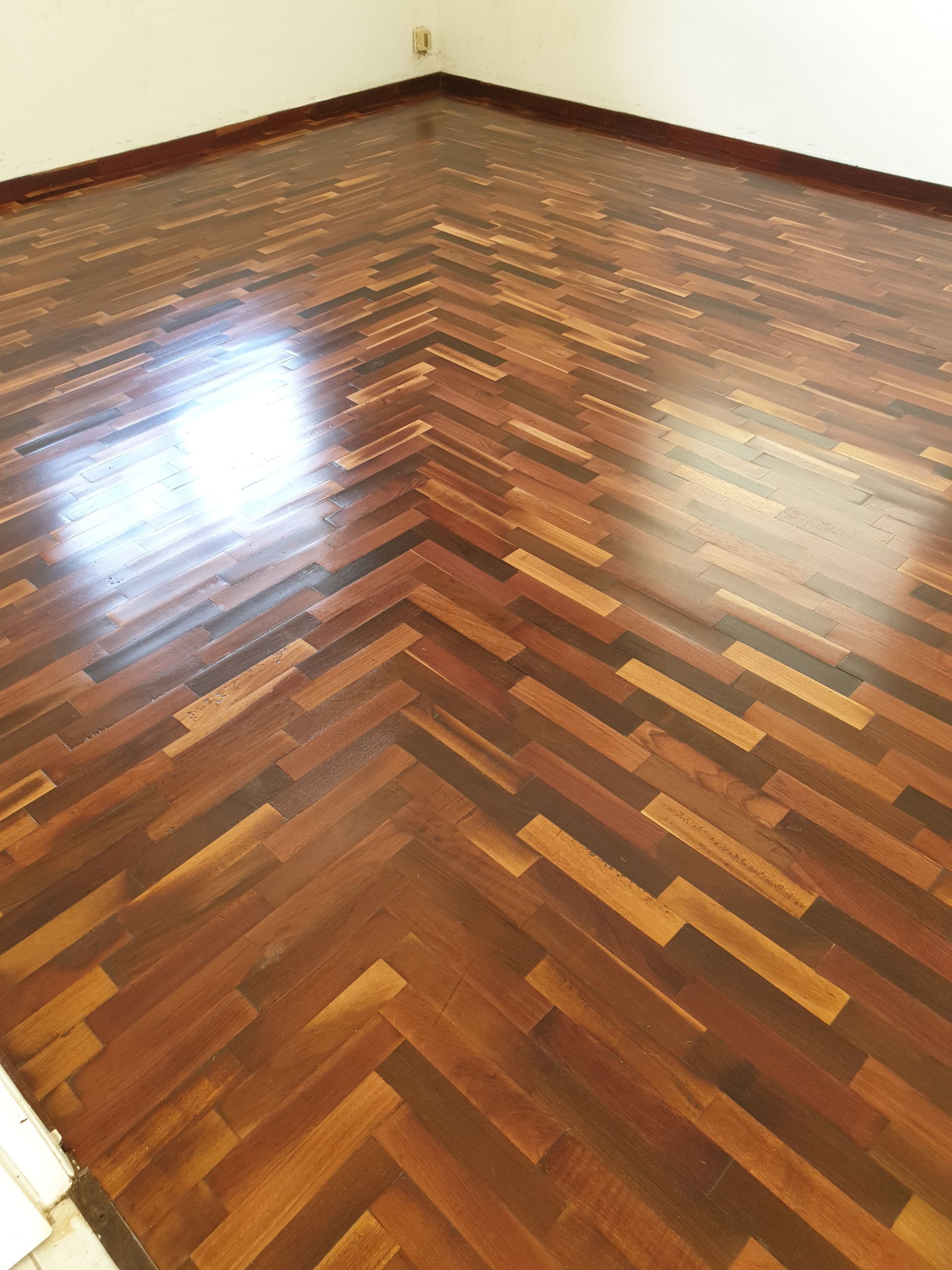 Pièce vide avec parquet en bois à chevrons brillant et murs blancs