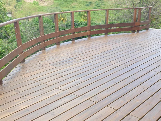 Terrasse en bois incurvée avec une balustrade donnant sur une colline verdoyante