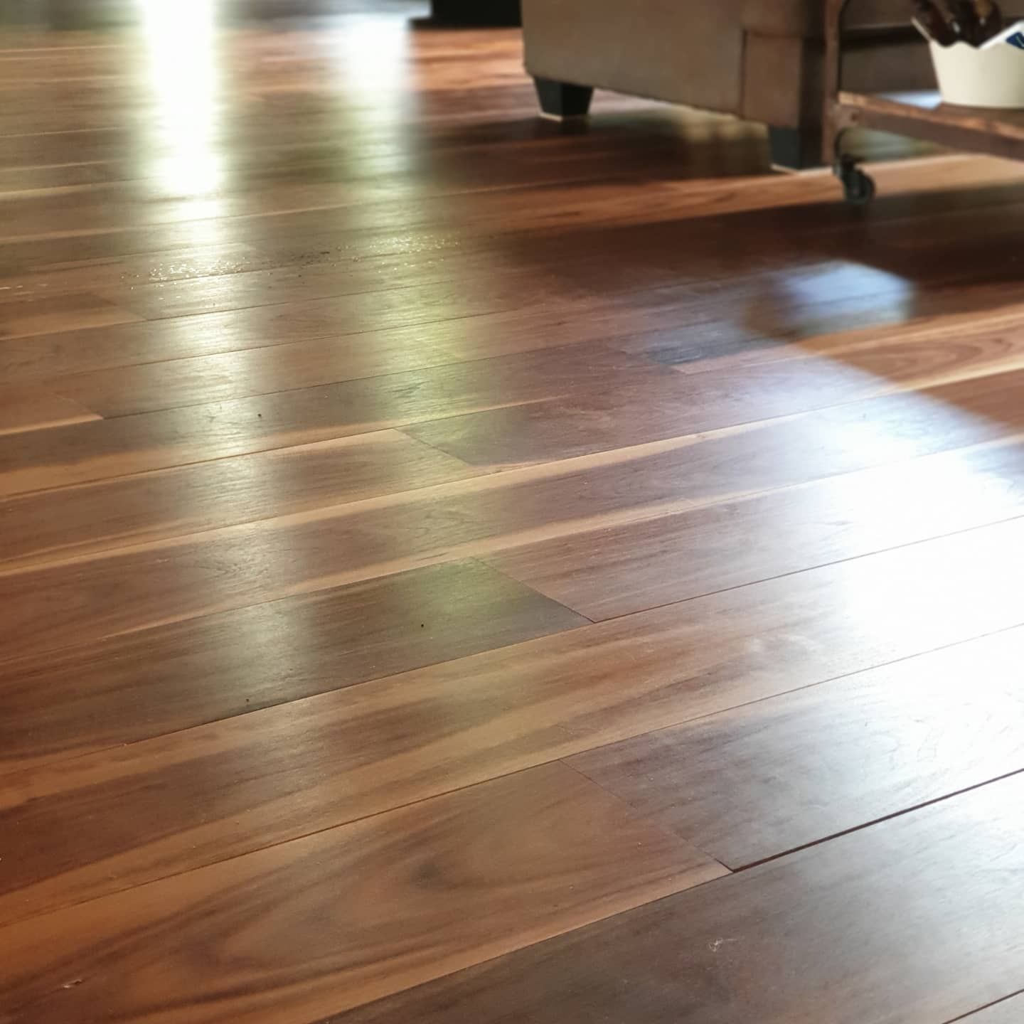Parquet brillant avec des reflets de soleil et une partie d’un canapé en arrière-plan