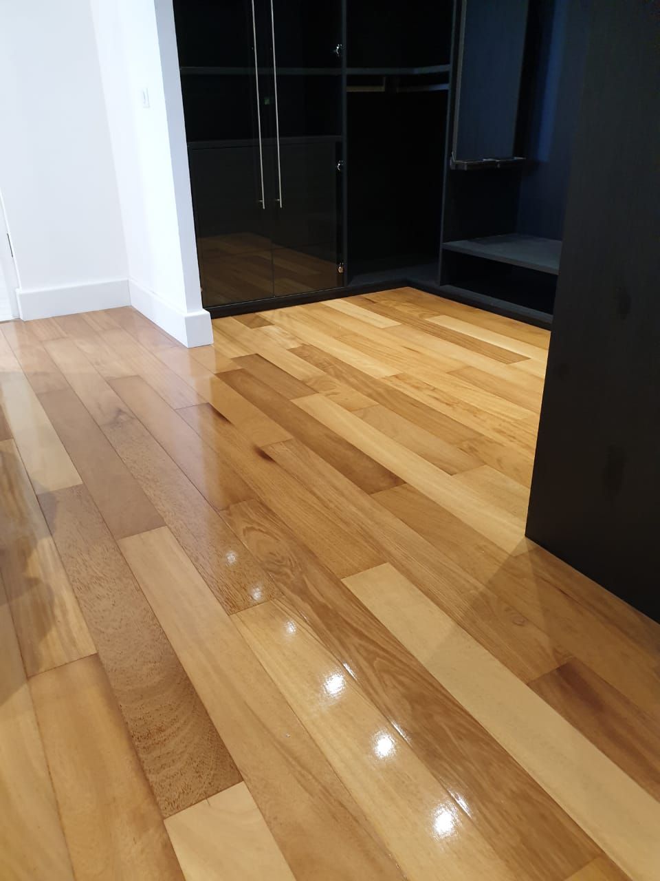 Parquet brillant à côté de murs blancs et d’une porte sombre dans une pièce moderne