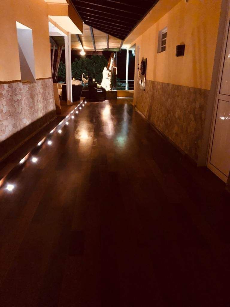 Couloir intérieur sombre, avec un sol brun brillant, des murs orange et des lumières sur le côté gauche.
