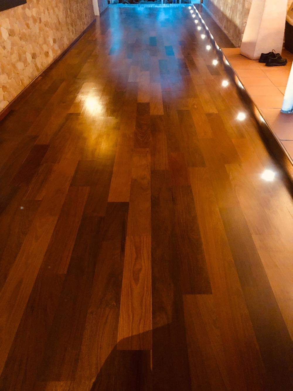 Couloir en bois poli, baigné d’une lumière chaleureuse, avec de petits éclairages au sol de chaque côté