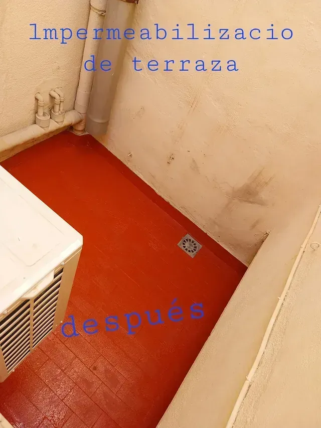 Terraza pintada de rojo tras la impermeabilización, junto a una pared blanca y un aire acondicionado, con desagüe en el centro. El texto dice