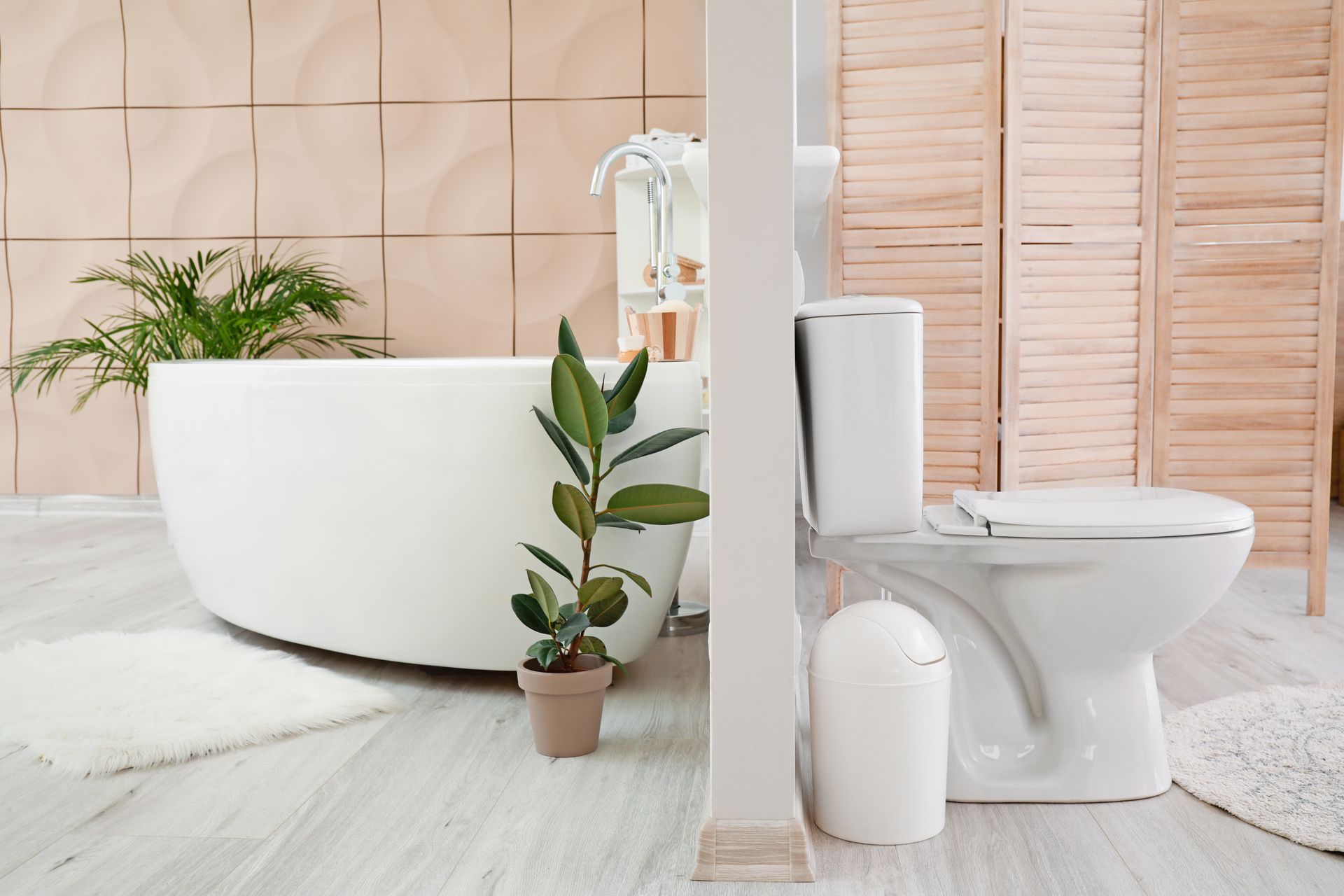 Salle de bains avec baignoire blanche, toilettes, plante en pot et éléments en bois clair.