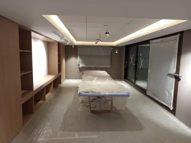 Sala moderna con una camilla de tratamiento, estanterías empotradas y grandes ventanales