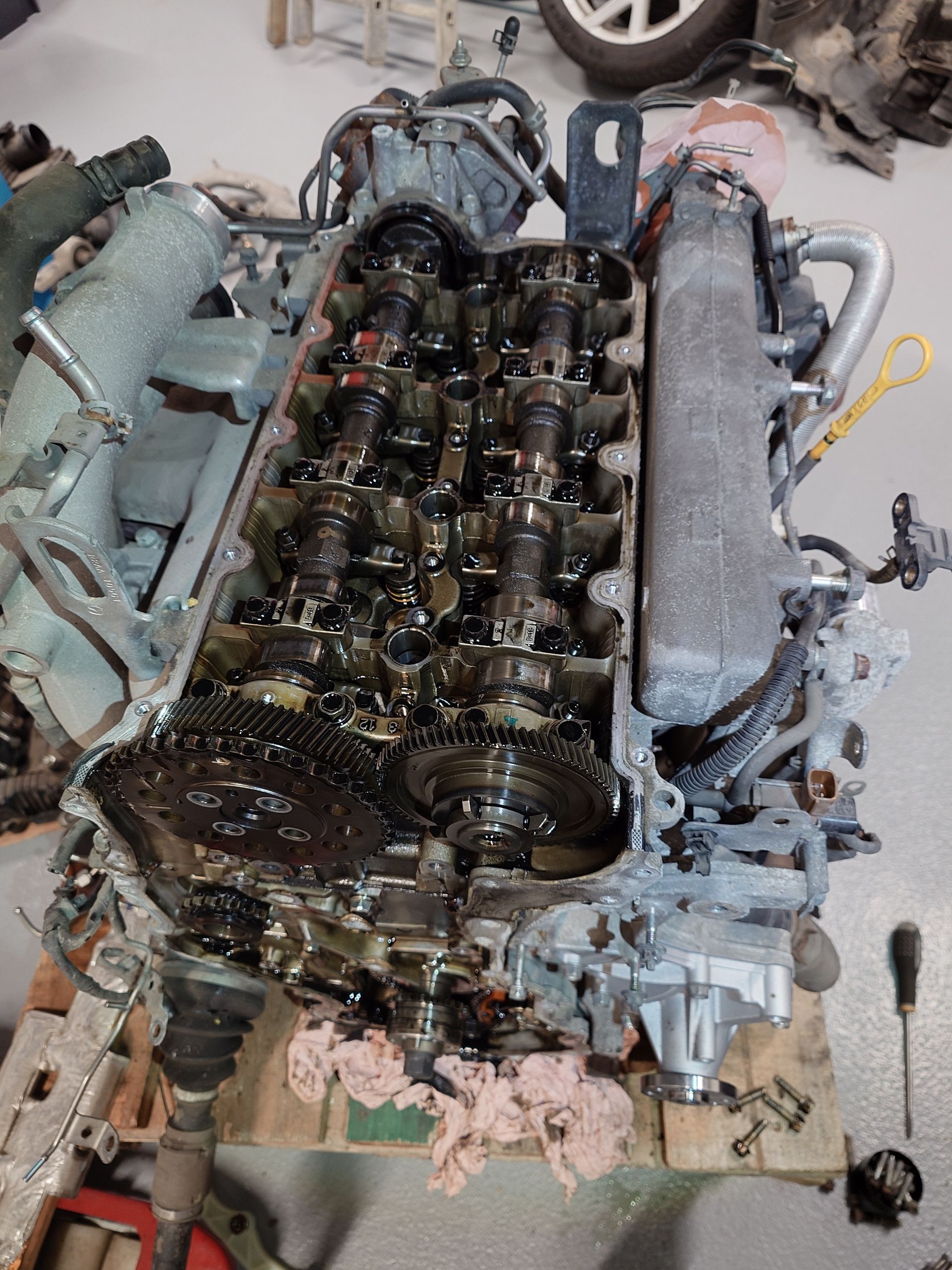 Vue de dessus d'un moteur, partiellement démonté, montrant les soupapes, la chaîne de distribution.