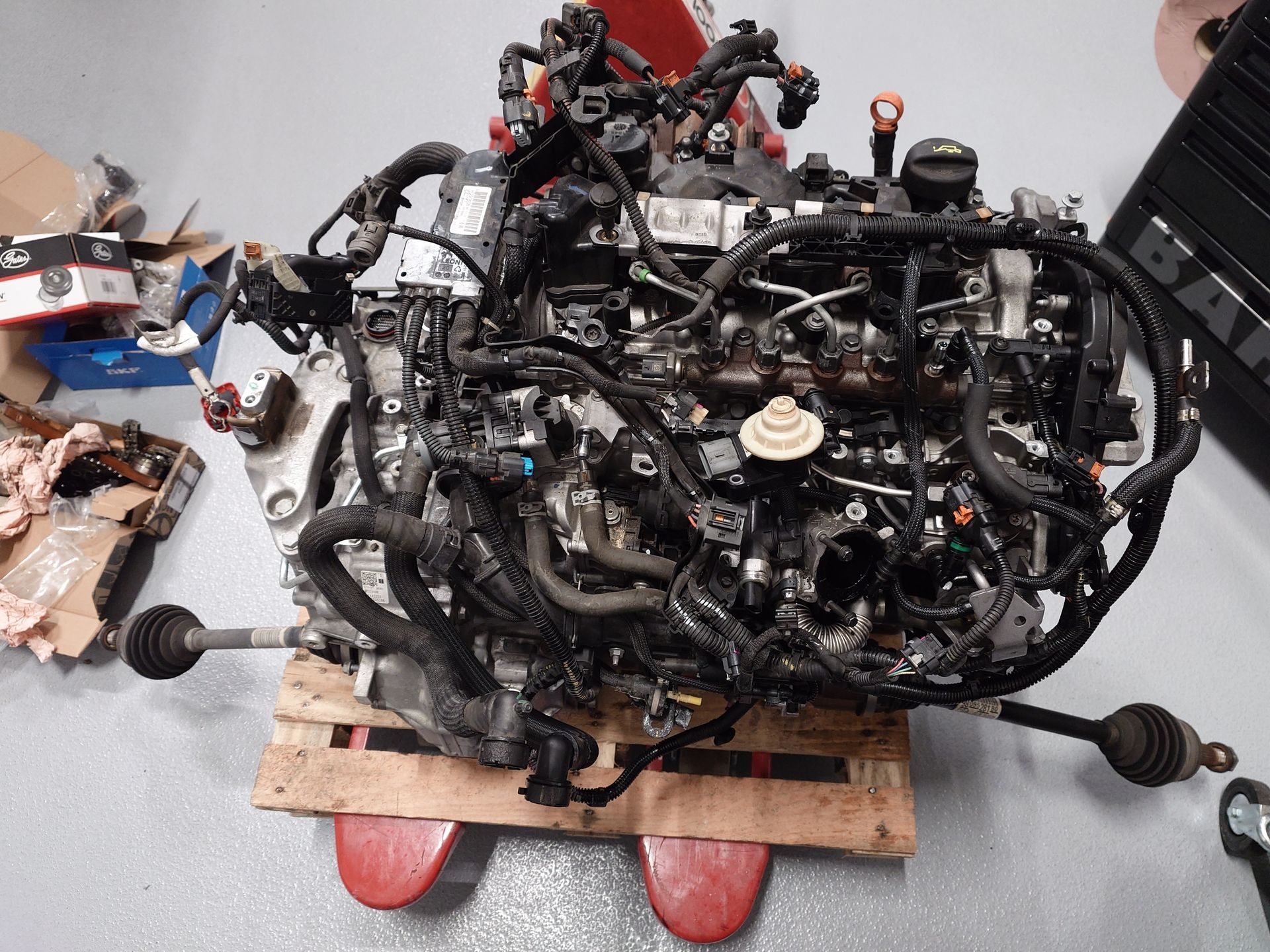 Moteur sur une palette, entouré de fils, de tuyaux et de composants mécaniques.