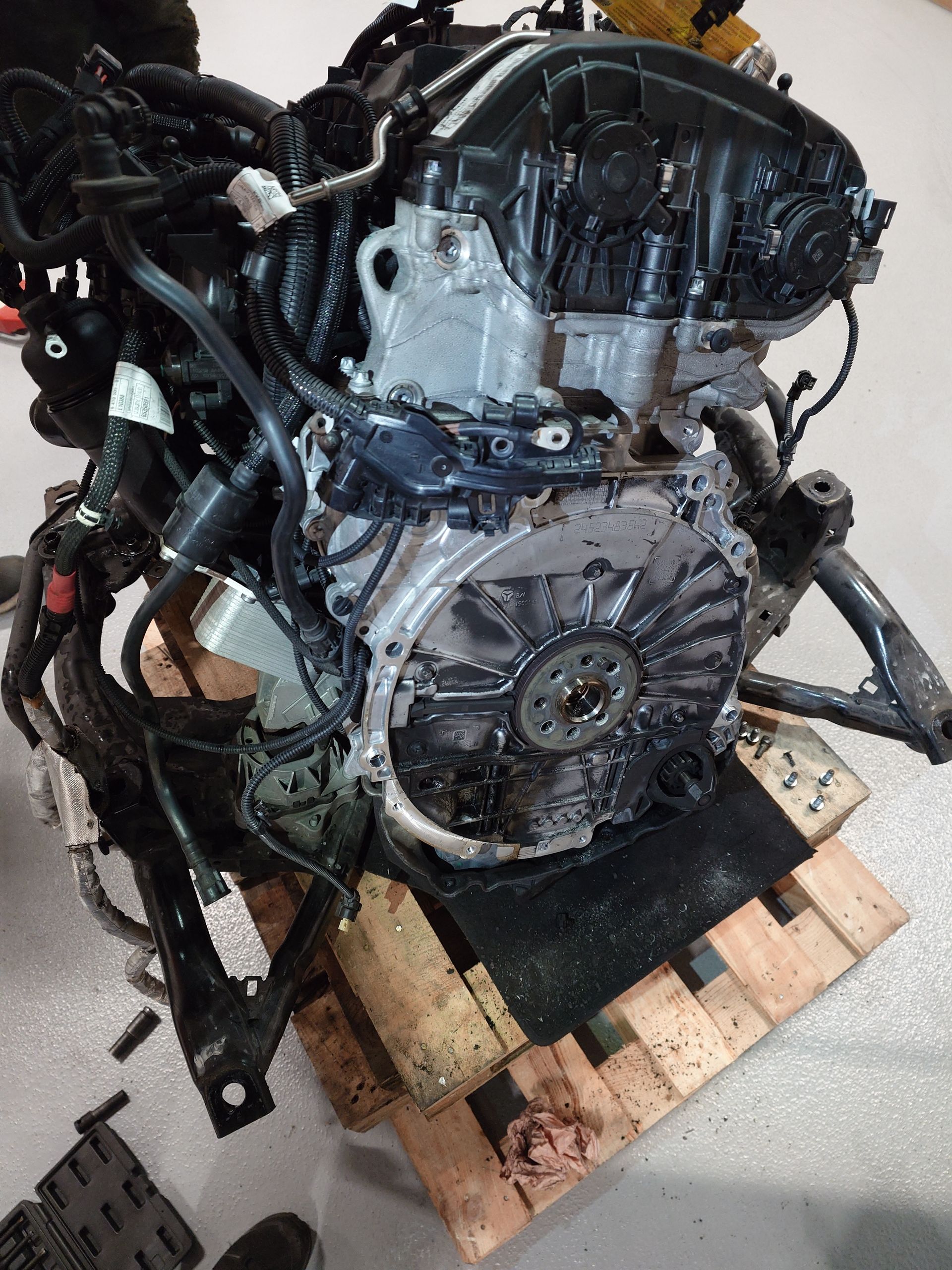 Moteur de véhicule noir sur une palette en bois dans un atelier.