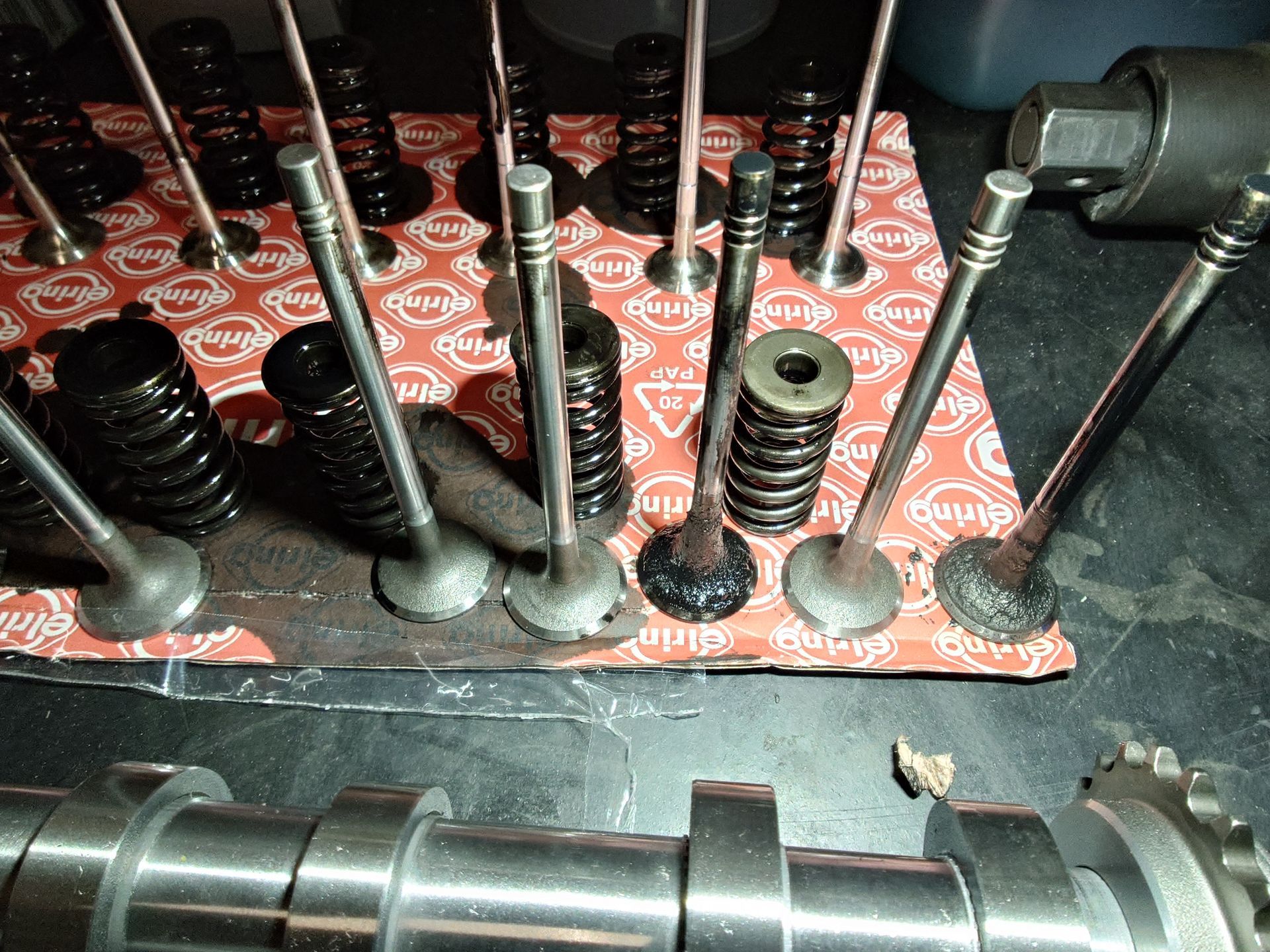 Soupapes et ressorts de moteur disposés sur une feuille de matériau de joint, avec un arbre à cames.