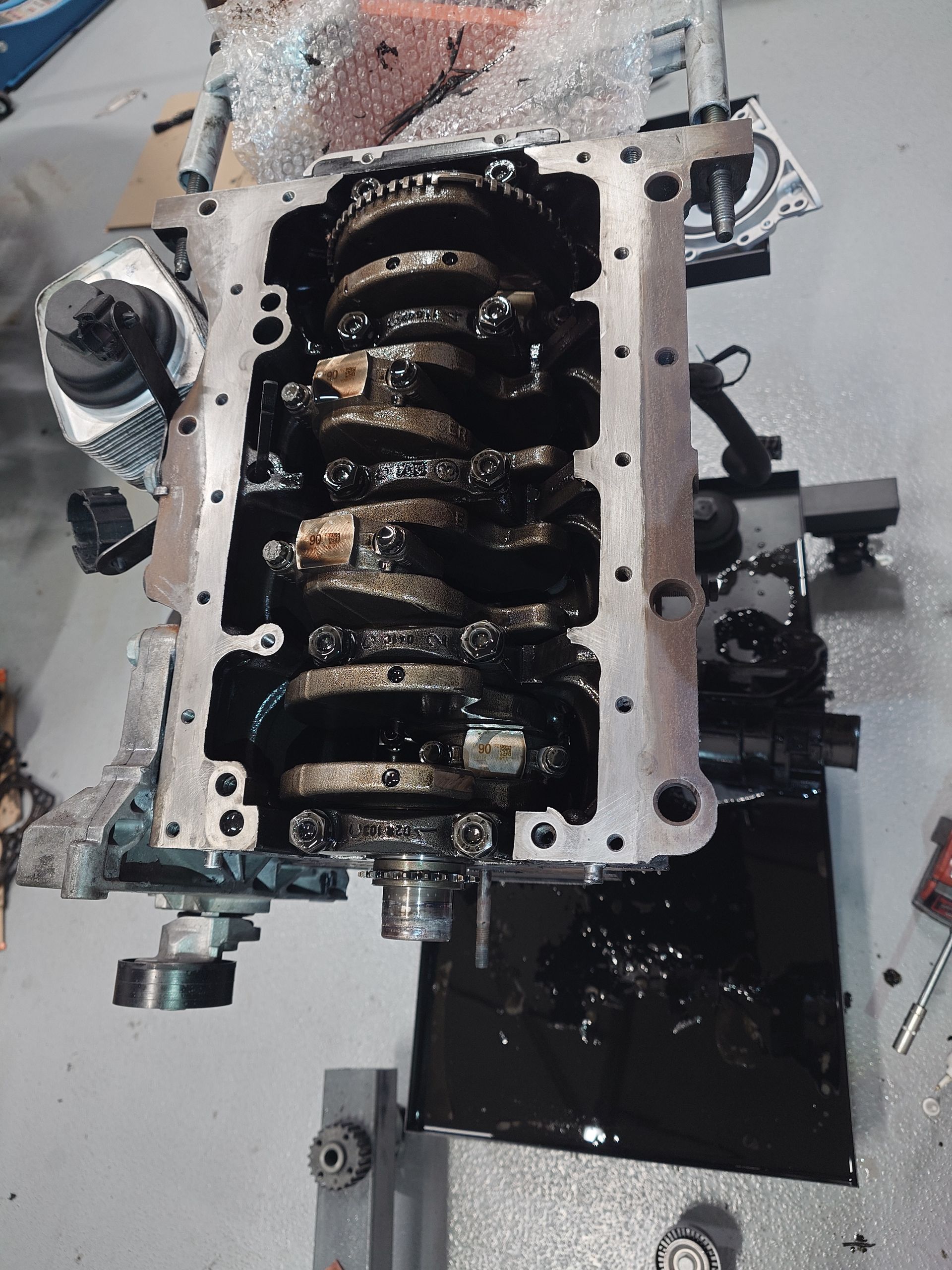 Bloc moteur avec vilebrequin visible, recouvert d'huile, sur un établi.