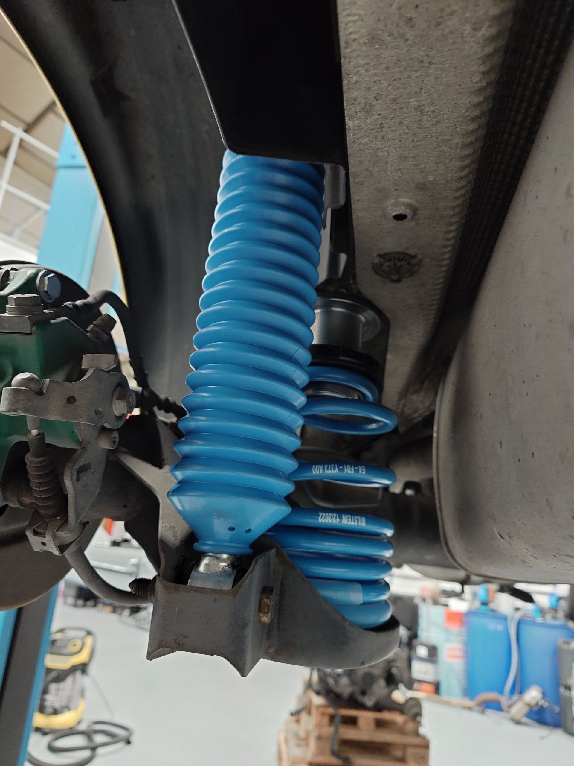 Amortisseur de suspension bleu installé sous le châssis d'une voiture.