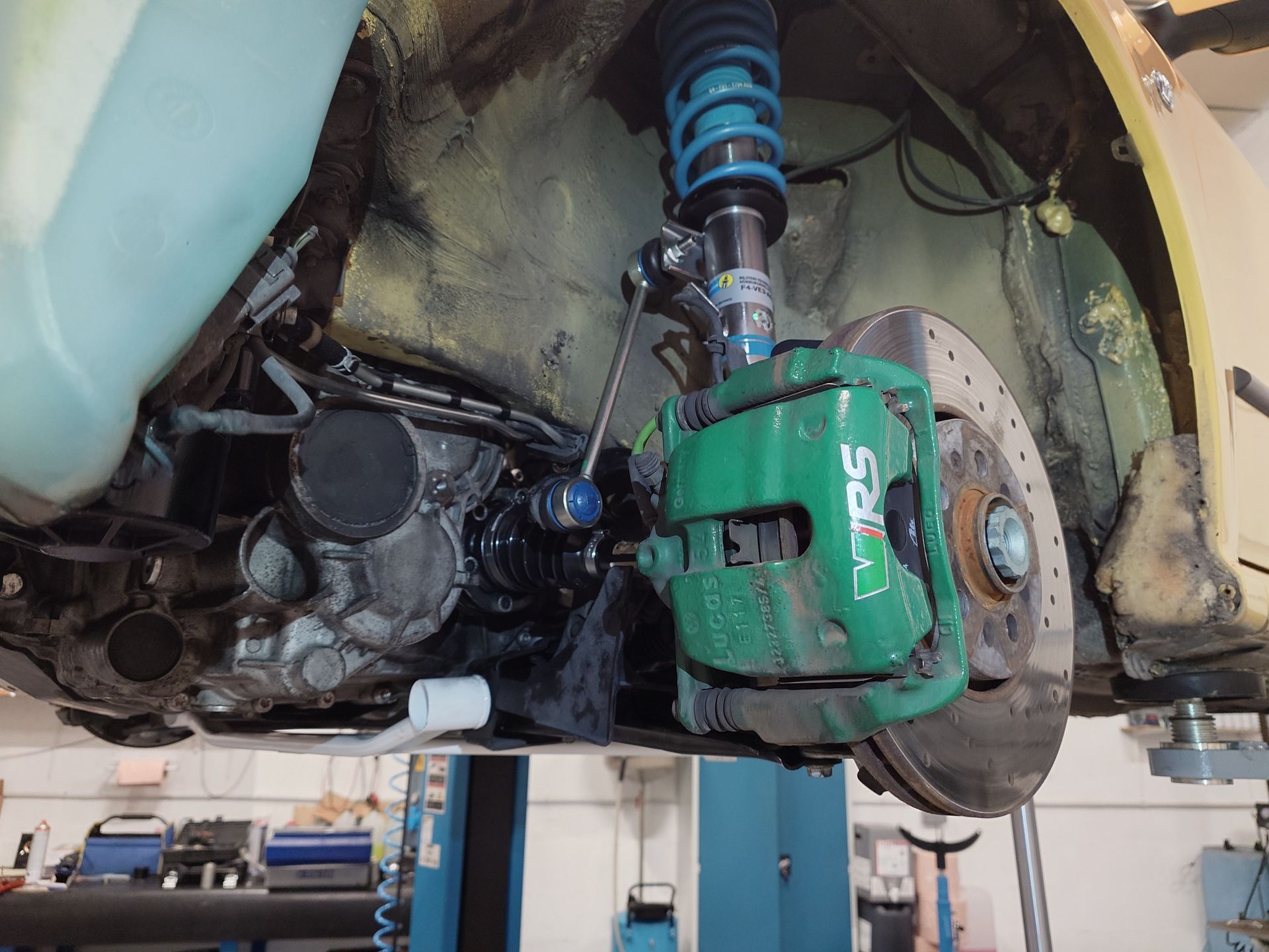 Étrier de frein vert et éléments de suspension sur une voiture jaune. Vue du train de roulement.