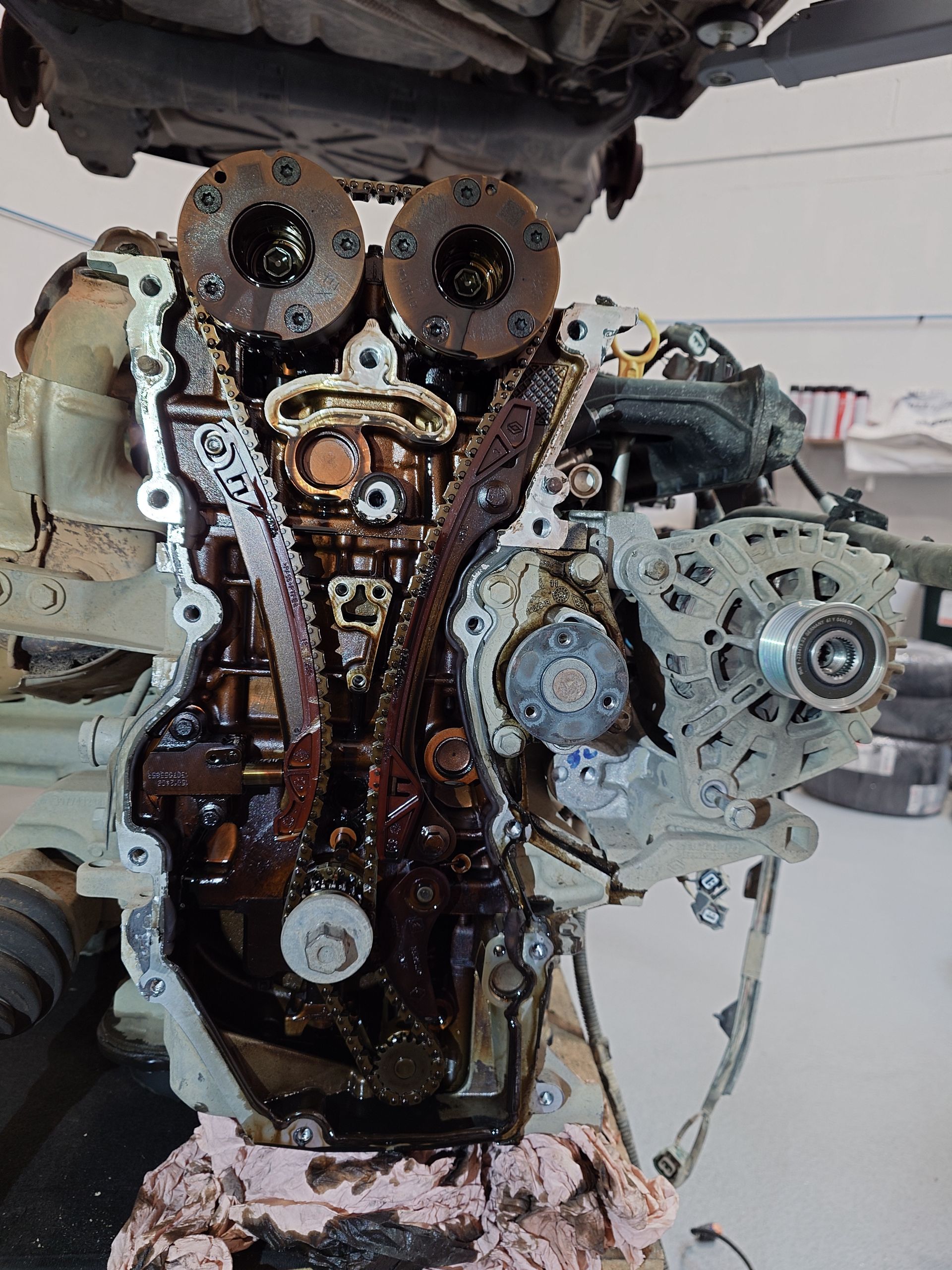 Moteur avec chaîne de distribution et engrenages exposés, recouverts d'huile, dans un atelier de réparation.