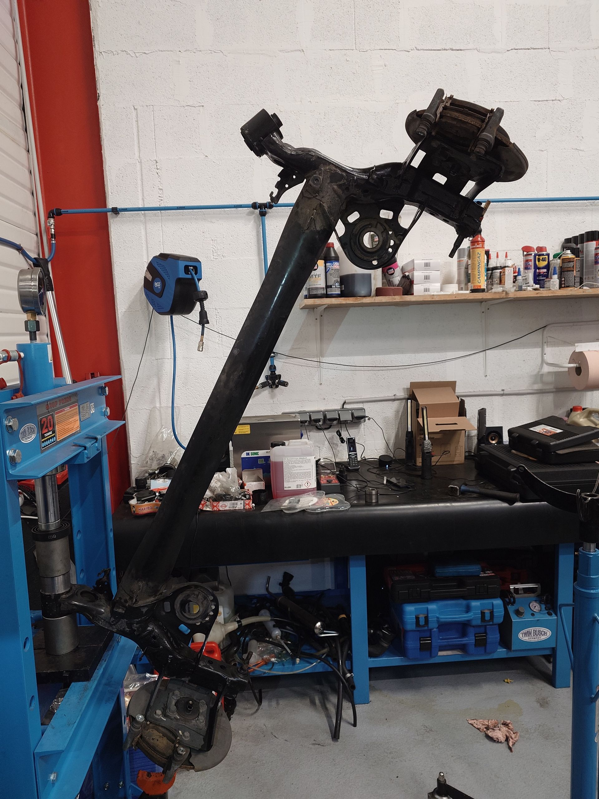 Un ensemble d'essieu automobile noir sur un établi avec des outils dans un garage.