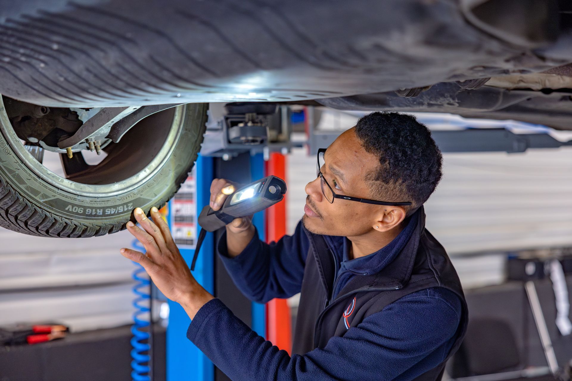 Un garagiste sous un véhicule en train de vérifier un disque de frein