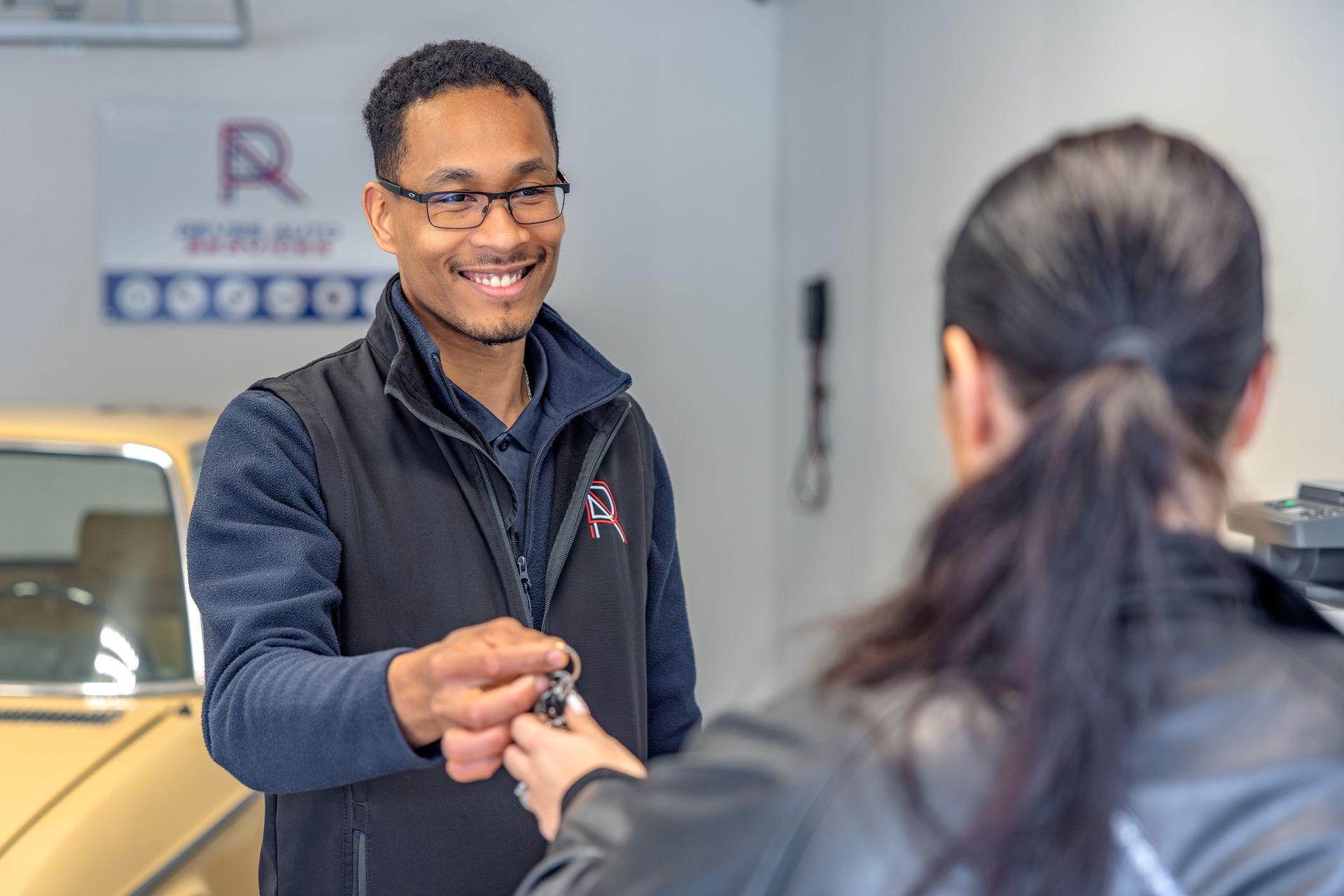 Mécanicien redonnant avec le sourire les clés d'une voiture à une cliente