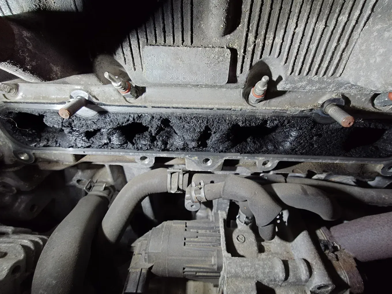 Gros plan sur le dessous sale d'un moteur ou d'une transmission, avec des boulons, des tuyaux et des composants métalliques