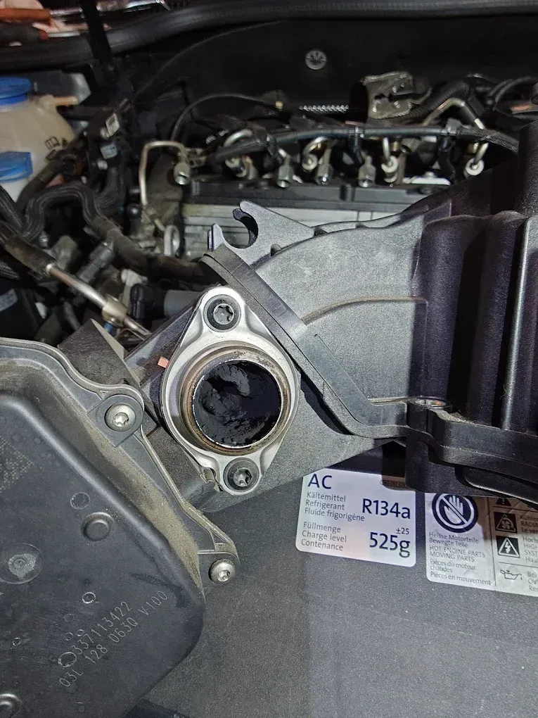 Gros plan sur le compartiment moteur d'une voiture, montrant l'ouverture de la prise d'air et un cache en plastique noir