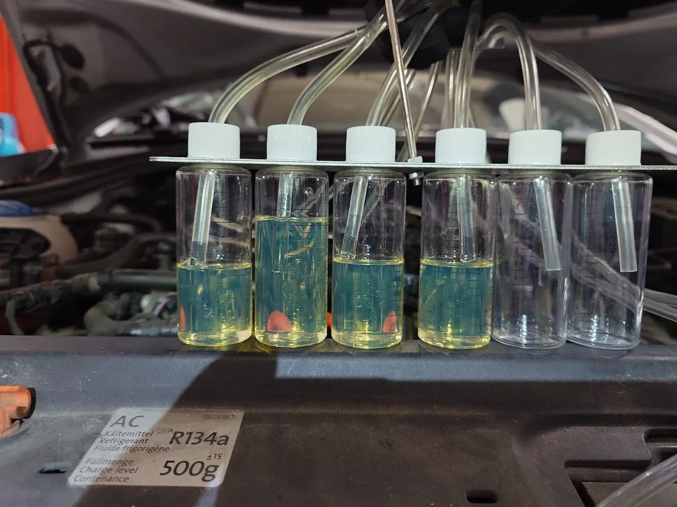 Six flacons transparents contentant du gasoil, afin de tester les injecteurs d'une voiture