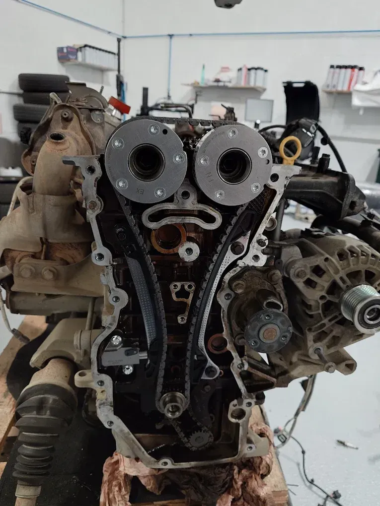 Vue de face d'un moteur de voiture démonté, avec ses composants de distribution visibles