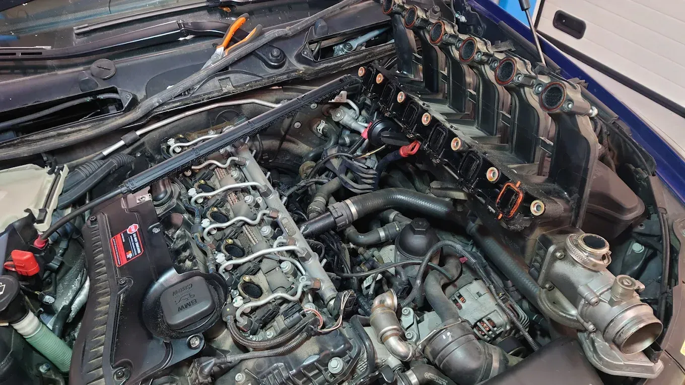 Capot d'une voiture ouvert pour montrer le compartiment moteur avec composants et câblage apparents, vu de dessus