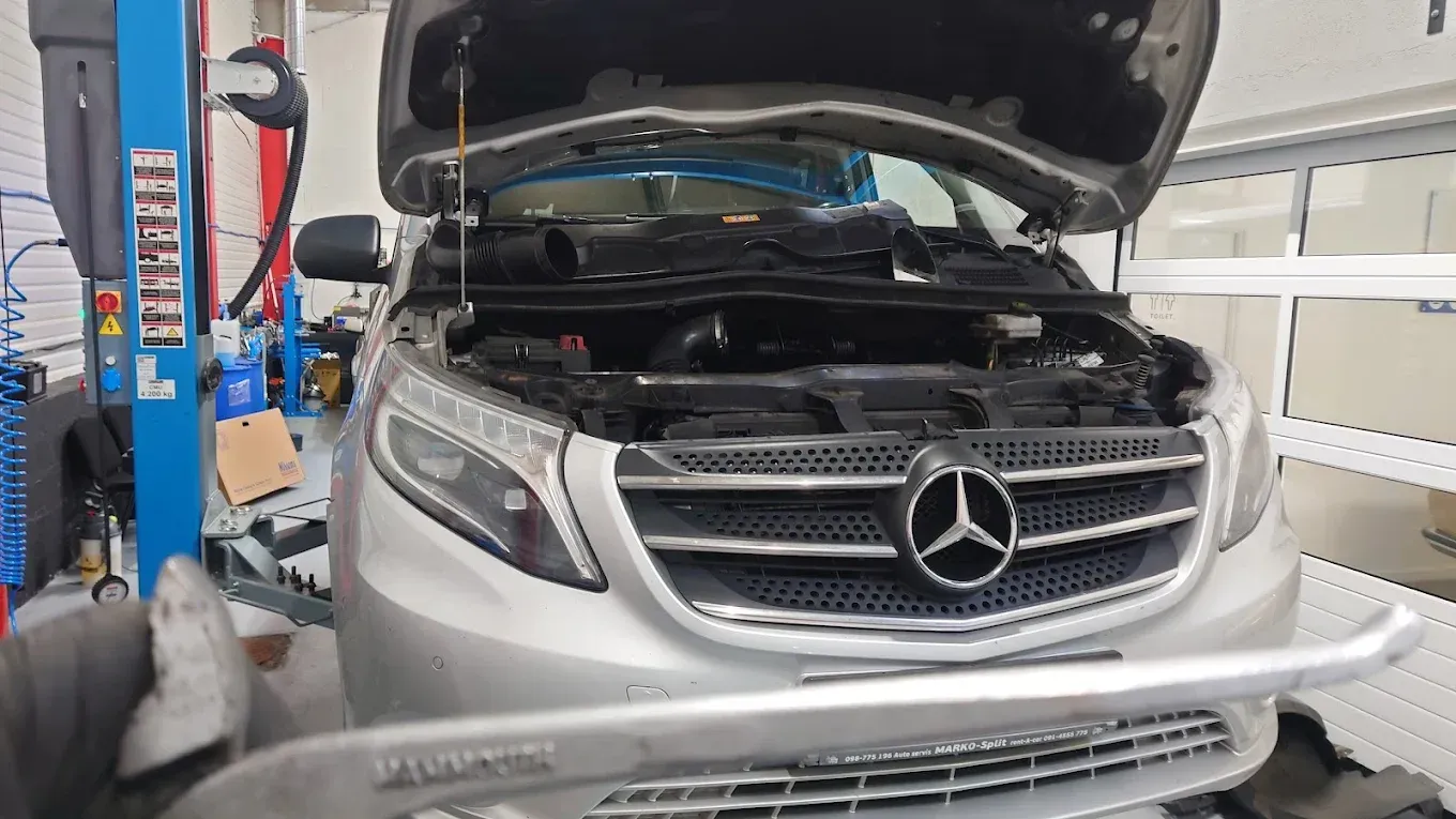 SUV Mercedes-Benz dans un atelier de réparation, capot ouvert, calandre et moteur apparents