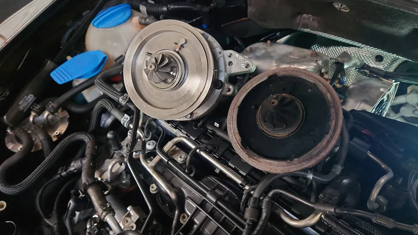 Compartiment moteur ouvert avec turbocompresseur et durites apparents, montrant des composants mécaniques en cours de réparation