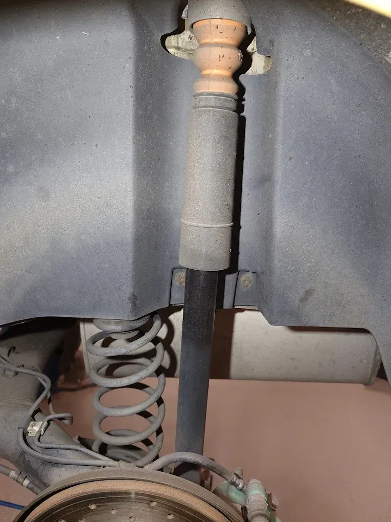 Suspension de pneu de voiture avec amortisseur et ressort hélicoïdal, à l'intérieur d'un passage de roue