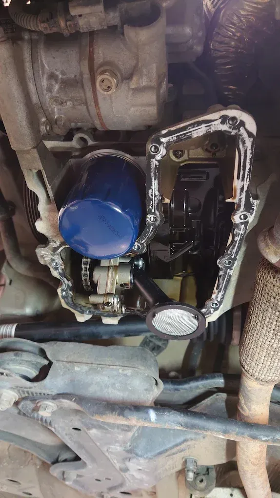 Vue du dessous d'un moteur de véhicule avec filtre à huile bleu et pièces de transmission apparentes