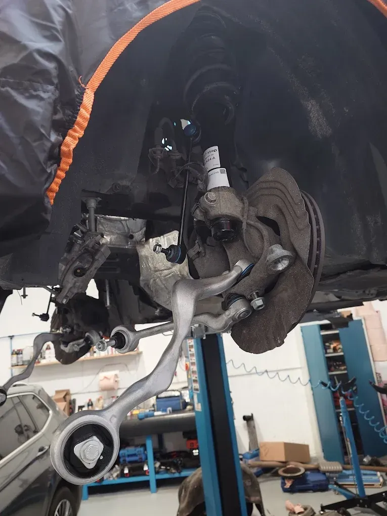 Roue et suspension d'une voiture exposées sous un véhicule surélevé, dans un atelier de réparation automobile