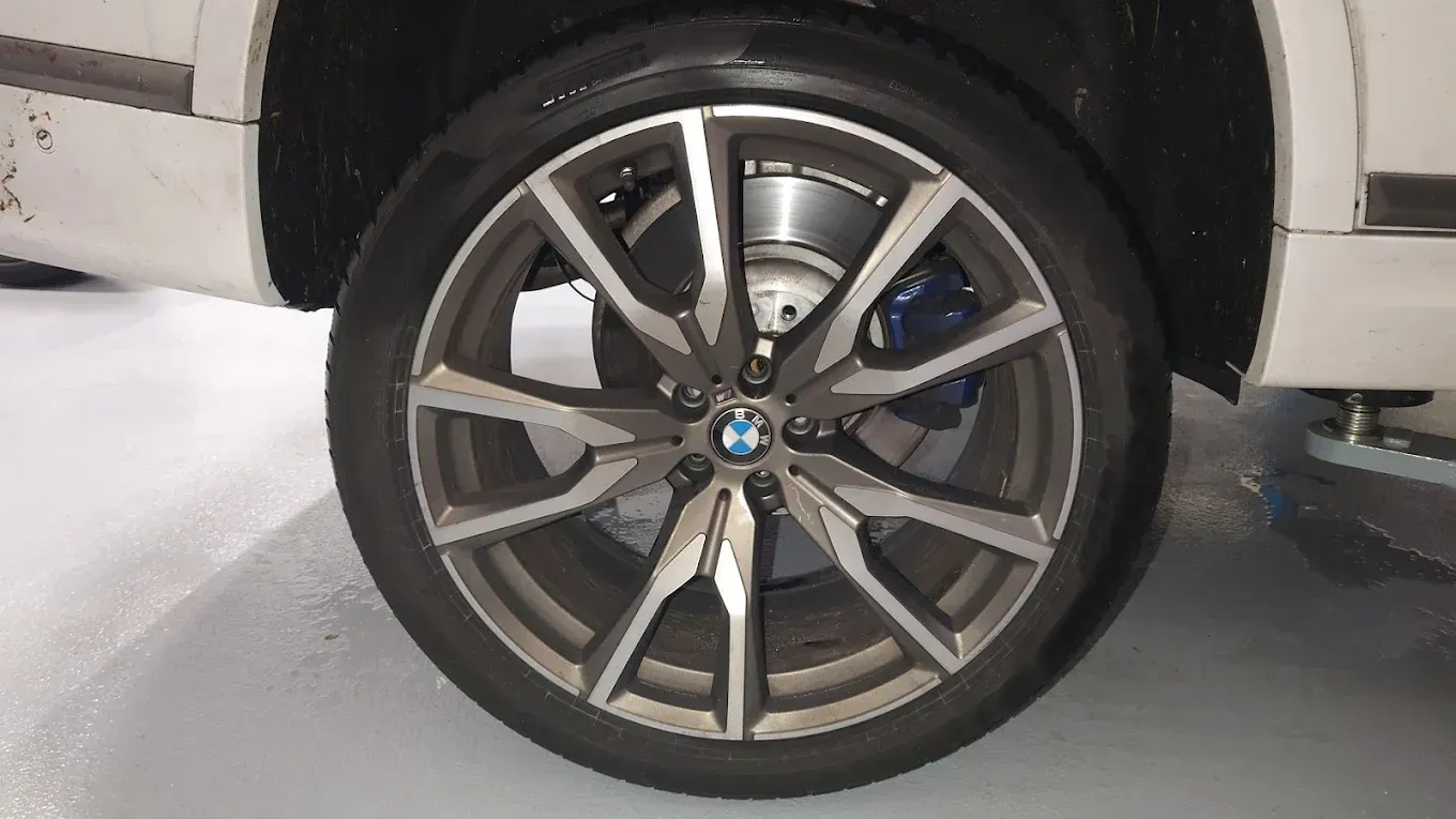 Gros plan sur une jante et un pneu BMW montés sur une voiture de couleur claire