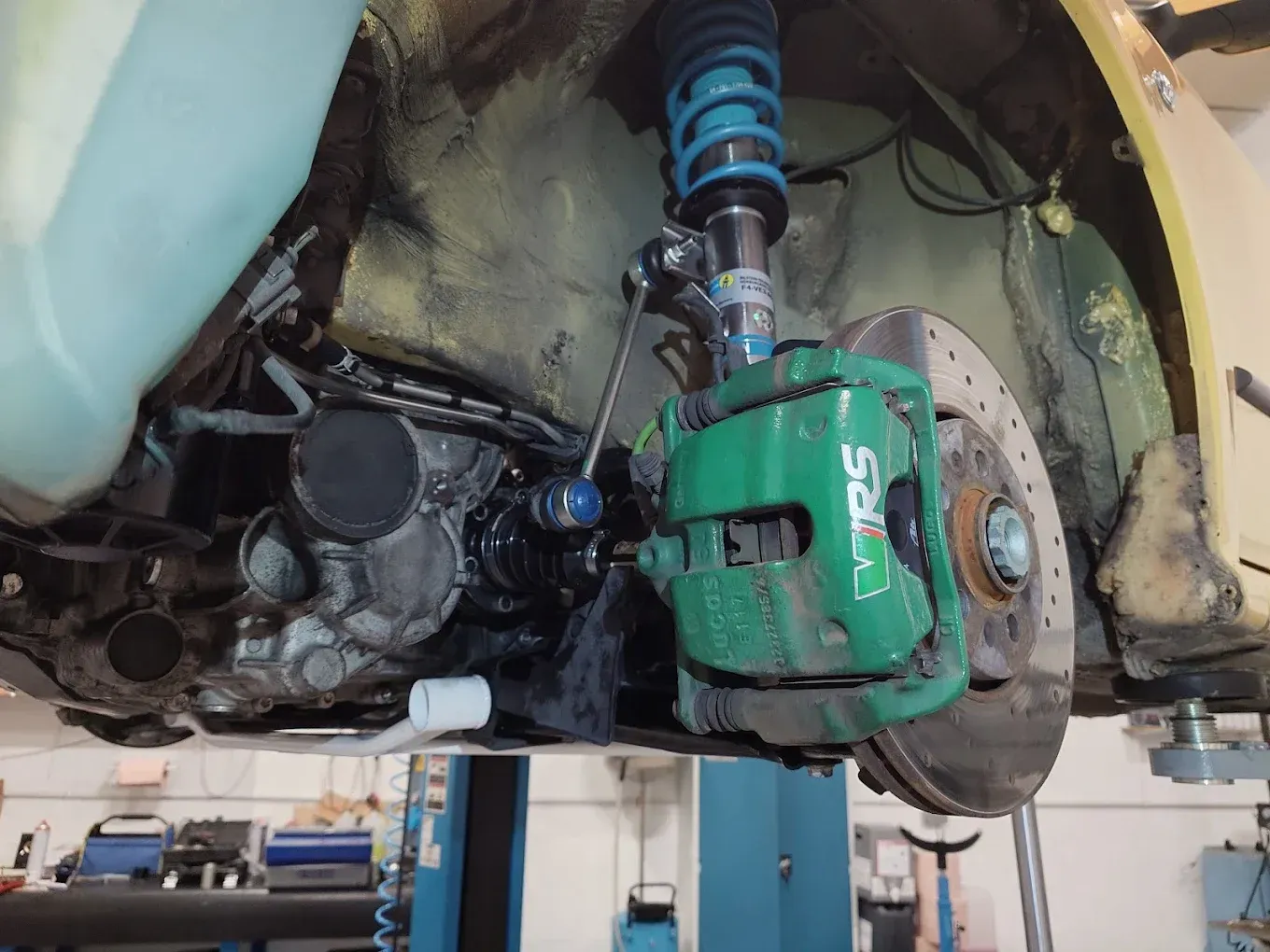 Suspension avant et système de freinage apparents d'une voiture, avec amortisseurs verts et moyeu de roue