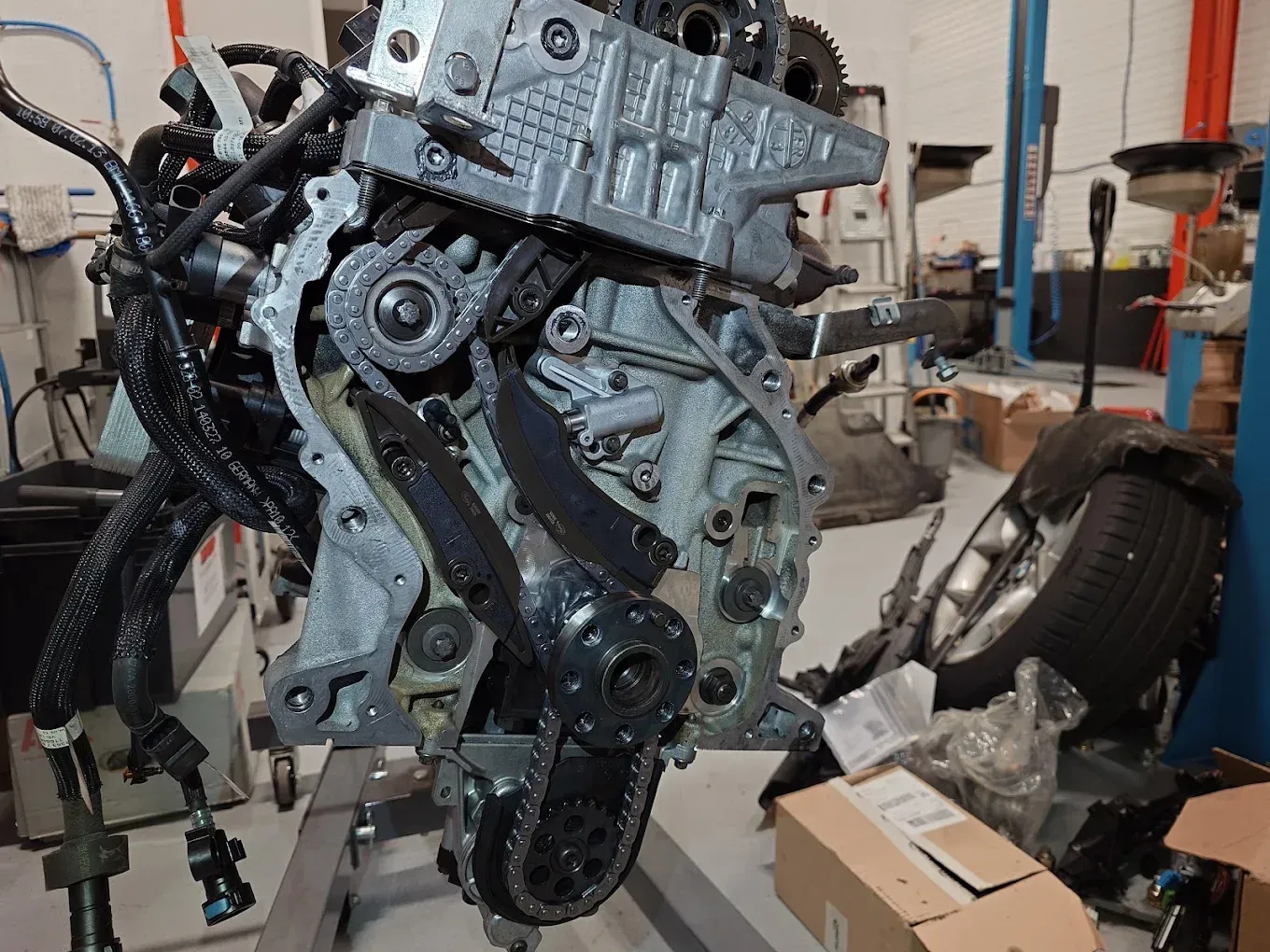 Moteur suspendu dans un atelier, pièces apparentes, outils et boîtes à proximité