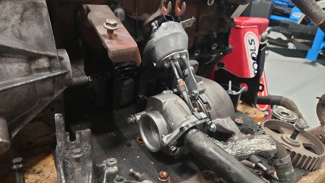 Gros plan sur un composant moteur endommagé, présentant une pièce métallique fissurée et des débris