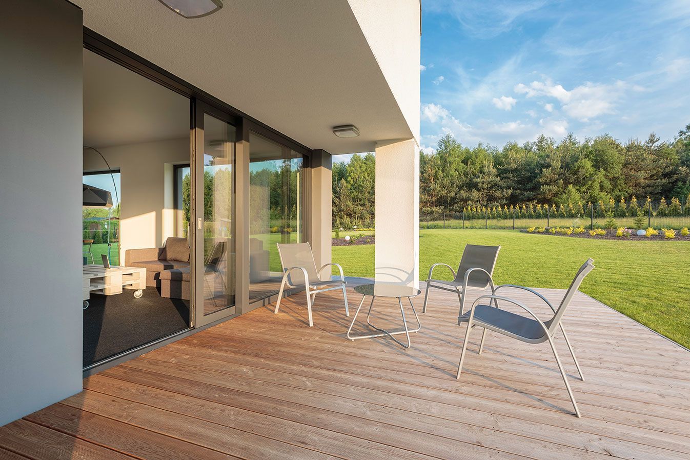 Cours d'une maison avec terrasse en bois et salon de jardin