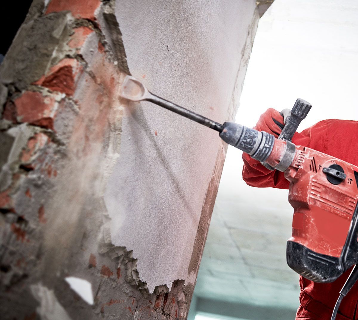 Homme qui utilise un perforateur pour démolir un mur