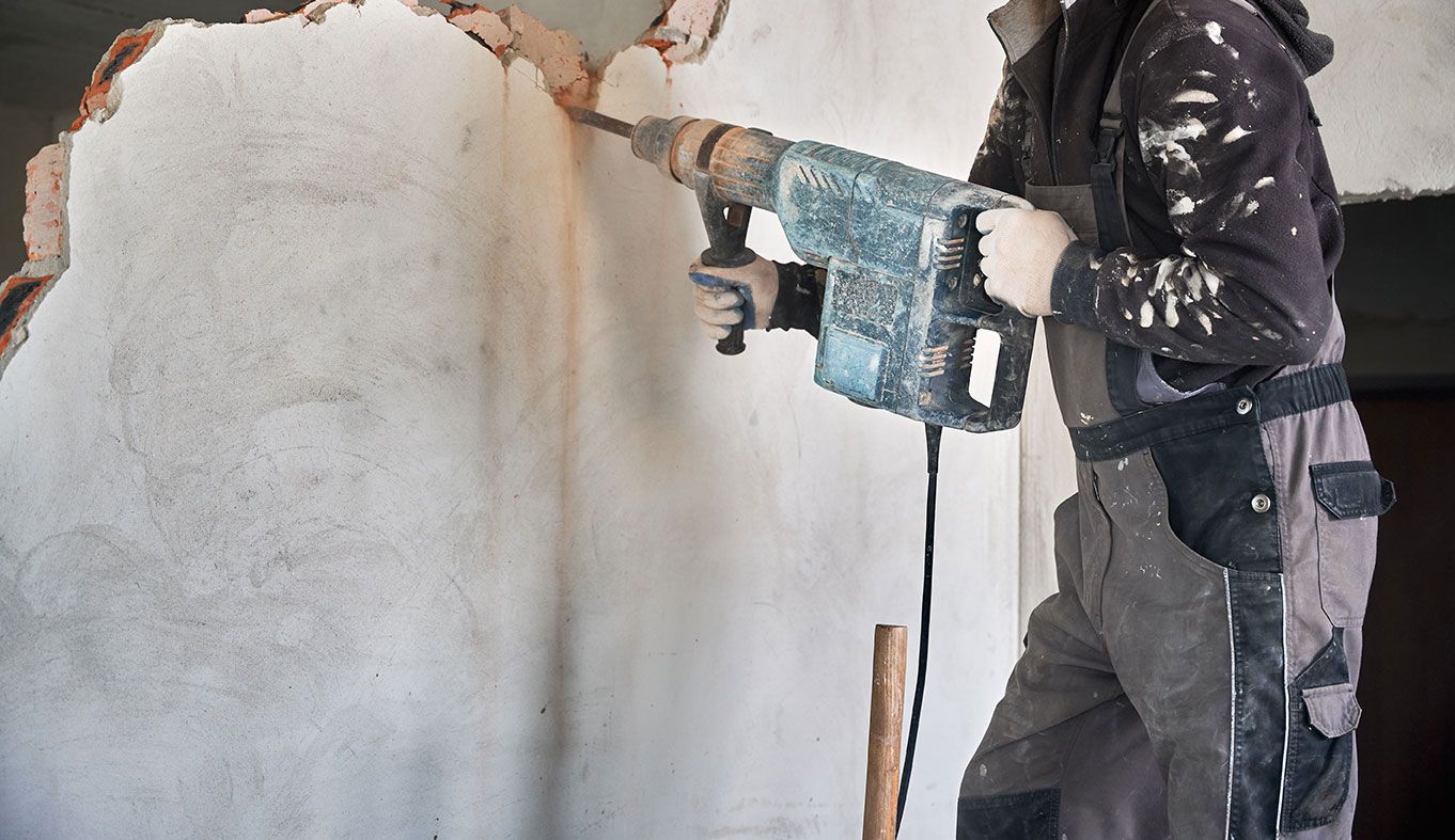 Homme qui utilise une perceuse à percussion pour creuser dans un mûr