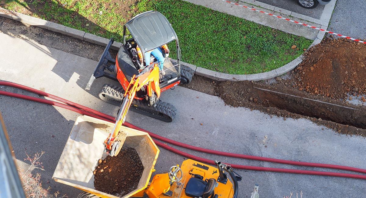 Minipelle qui creuse une tranchée sur une route
