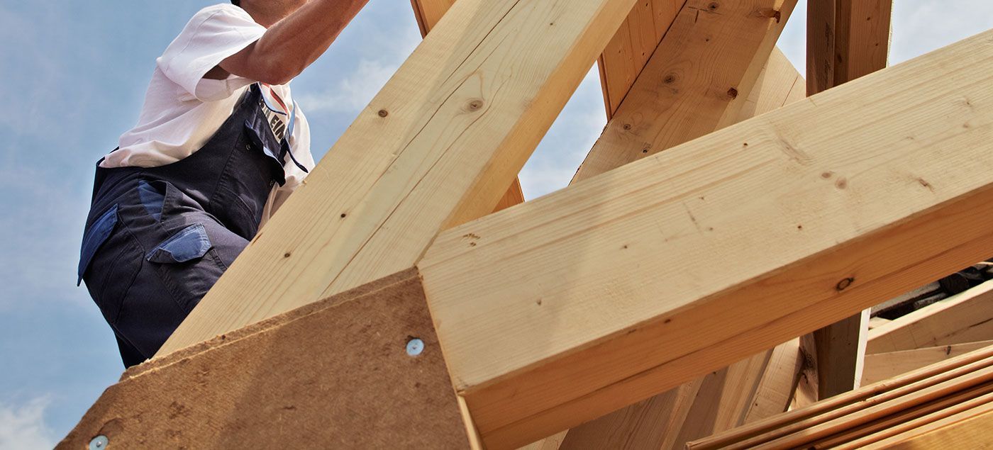 Ouvrier entrain de fixer les poutres d'une charpente