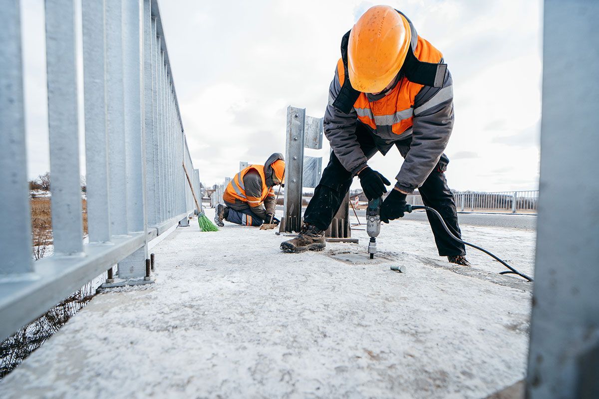Ouvriers qui installent des barrières de sécurité sur un pont