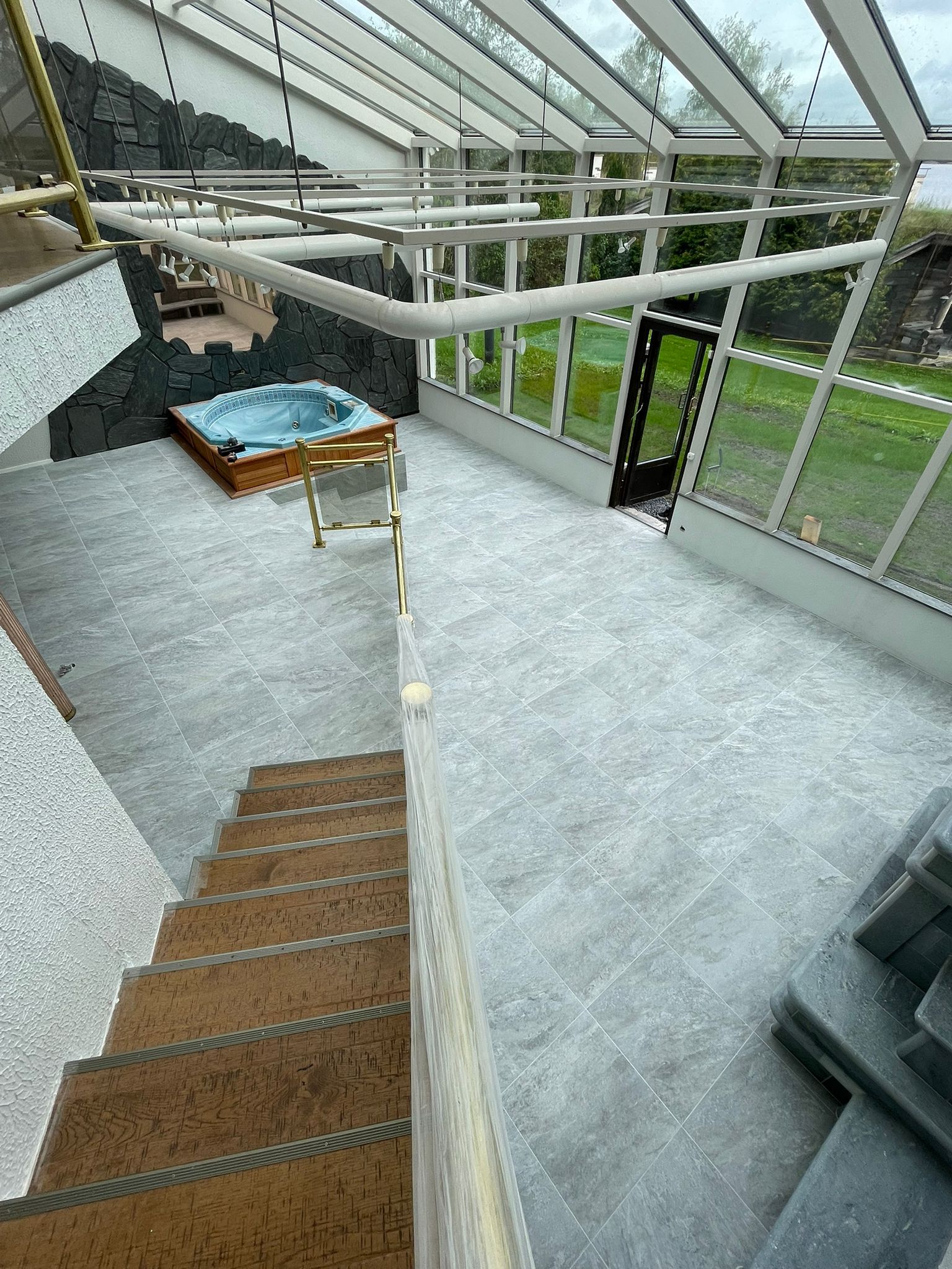 Lasinen atrium portailla, sisävehreys ja istuinryhmä sinisellä tyynyllä.