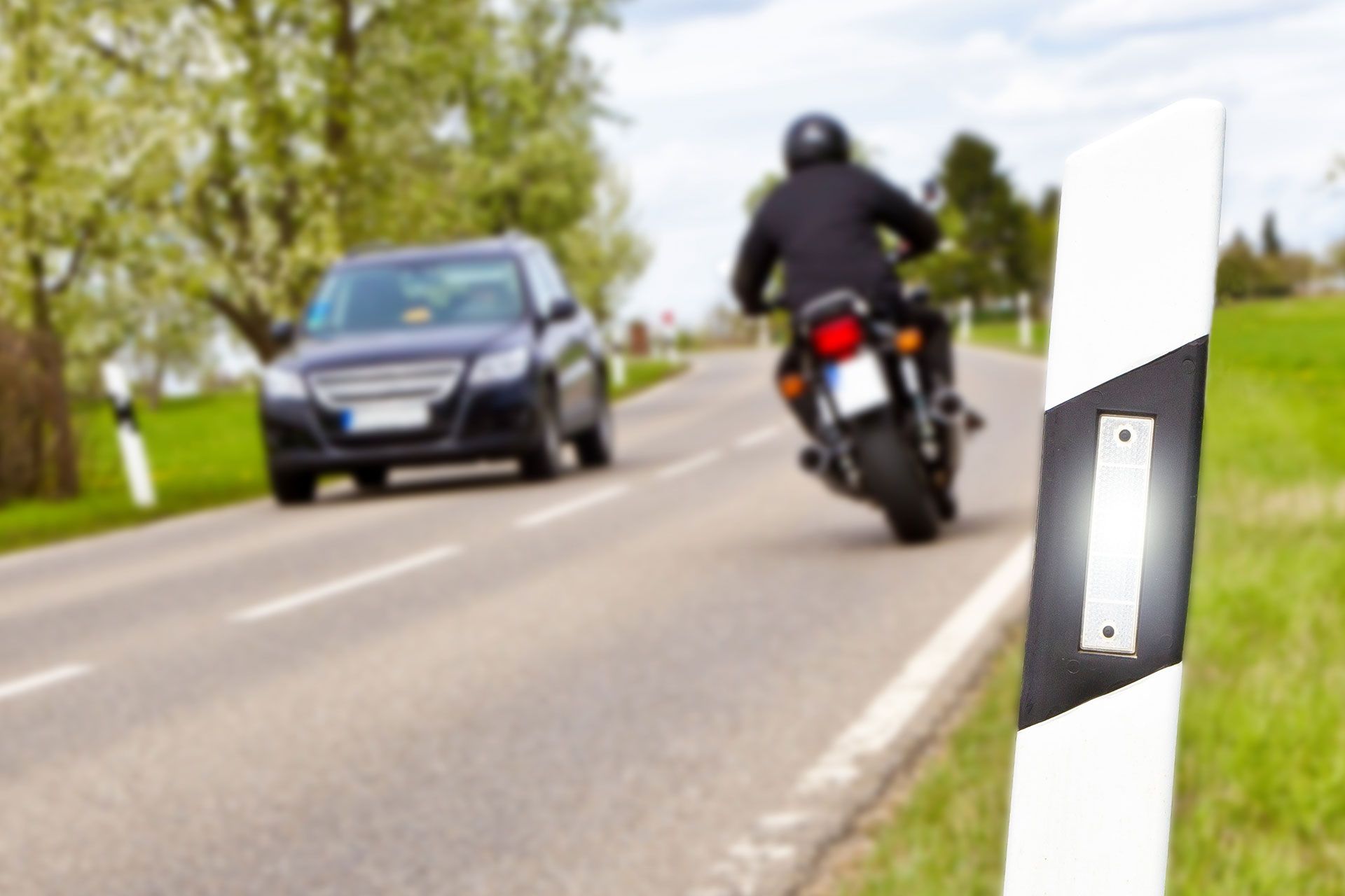 Ein Motorrad fährt auf einer Straße neben einem Auto her.