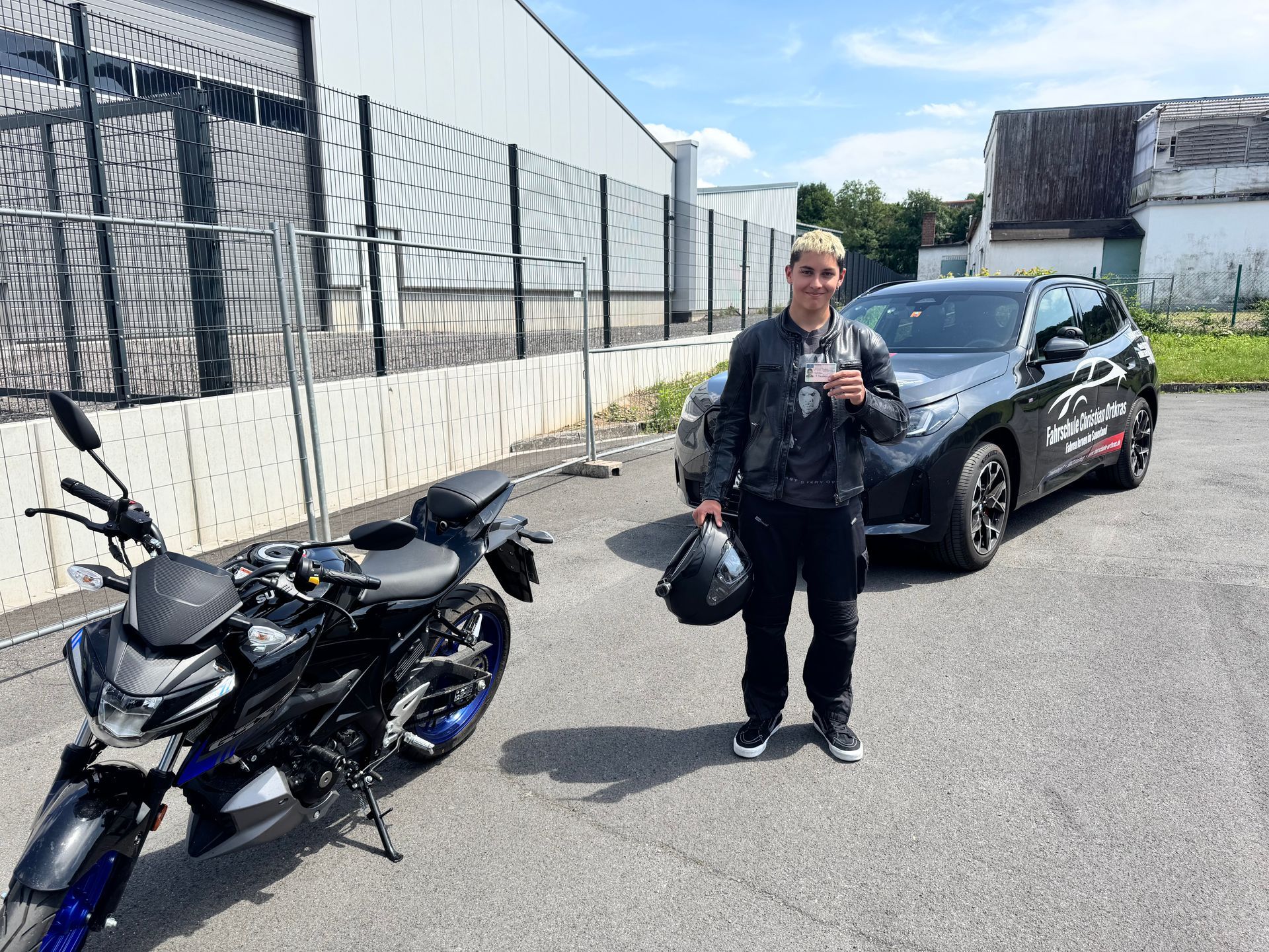 Ein Mann steht neben einem Motorrad und einem Auto.