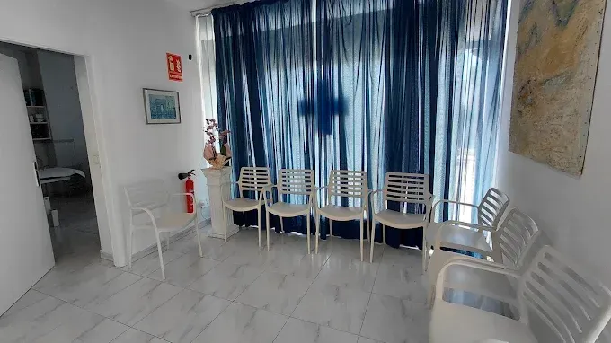 Sala de espera con cortinas azules, sillas blancas