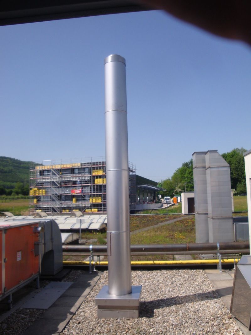Ein grosses Metallrohr liegt auf einem mit Kies bedeckten Dach