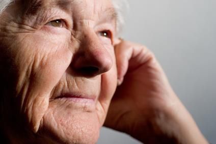 Eine Nahaufnahme des Gesichts einer älteren Frau, die die Hand am Ohr hält.