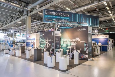 Messestand für „Electronic City“ mit ausgestellten Produkten und anwesenden Personen.
