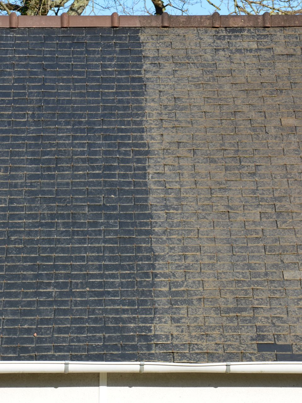 Les bardeaux de toiture foncés, nettoyés, sont visibles à droite, contrastant avec les bardeaux sales et noircis à gauche.
