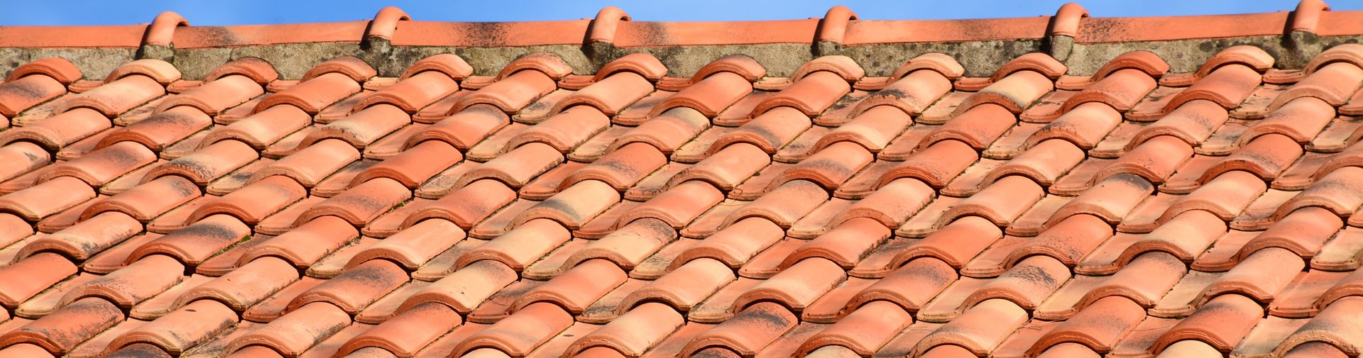Toit de tuiles en terre cuite sur un ciel bleu.
