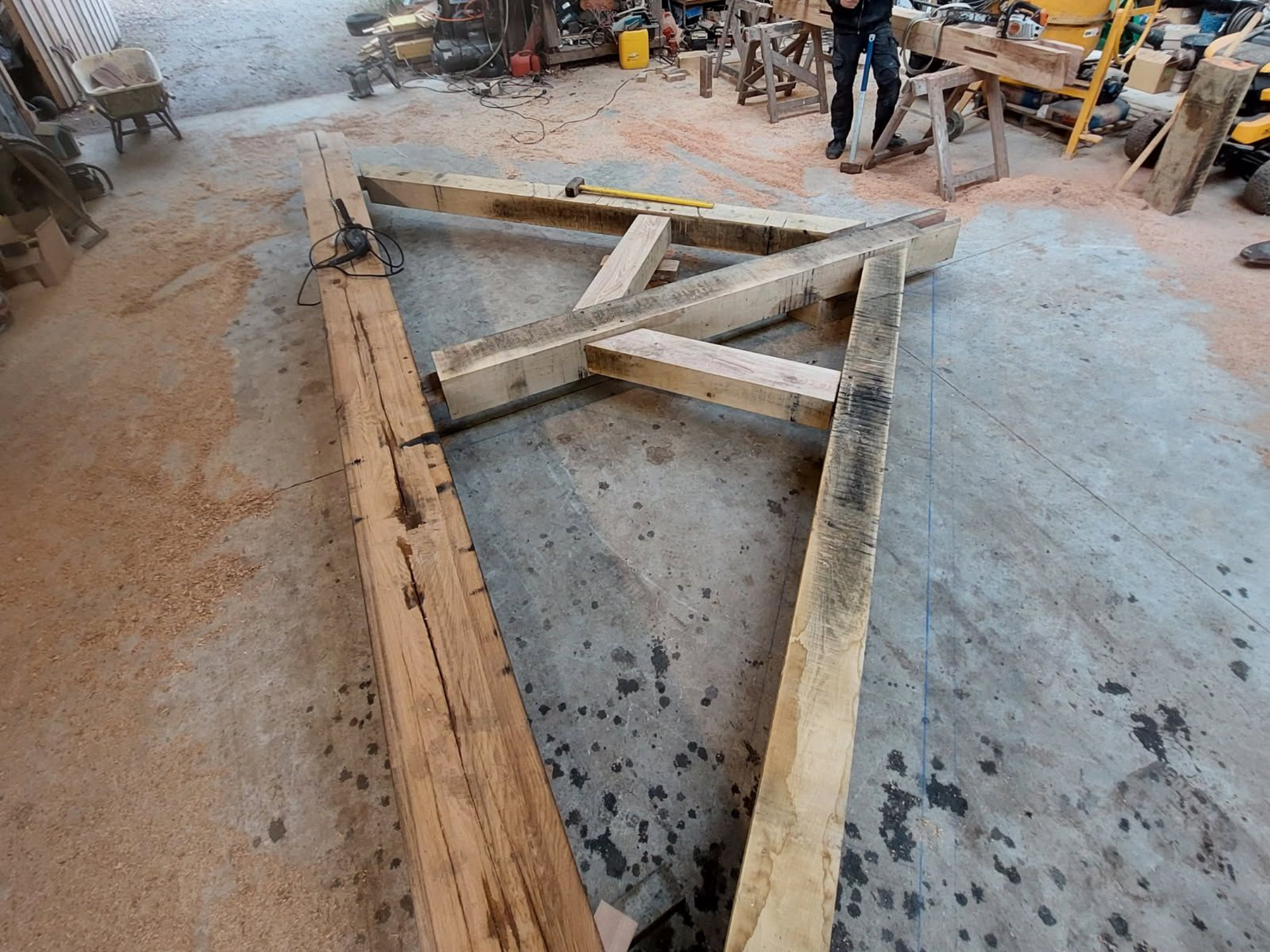 Construction à ossature bois dans un atelier, pièces disposées sur un sol en béton.